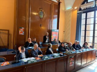 Conferenza stampa nella Sala Consiliare del Comune di Foggia per la presentazione dell'ITF Men's World Tennis Tour M15. Al tavolo dei relatori, amministratori locali e rappresentanti del Tennis Club Foggia. Sullo sfondo, uno stemma ligneo e banner dell'evento.